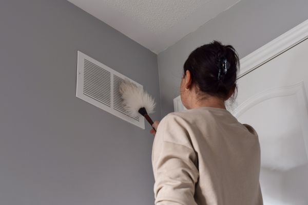 A woman brushing out the return air grille
